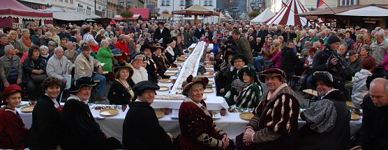 Die Honoratioren Eislebens, Vertreter der Kreisverwaltung, Menschen mit dem Nachnamen Luther und Geburtstagsg&auml;ste aus dem Publikum heute Nachmittag an der auf dem Marktplatz der Lutherstadt aufgebauten Tafel. Vor ihnen eine elf Meter lange Stolle, die anschlie&szlig;end gemeinsam mit dem Publikum vernascht wurde. (Foto: Jochen Miche)