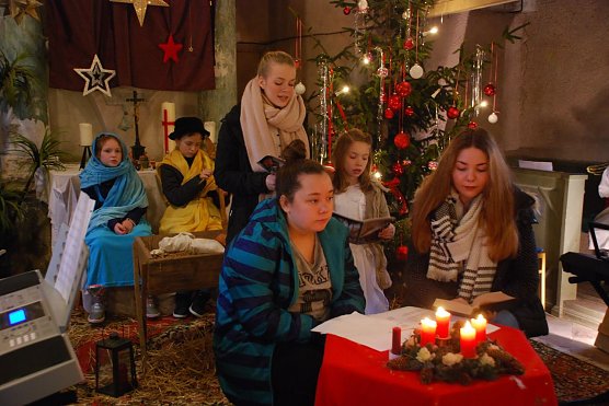 In dieser Szene sehen wir hinten Maria und Josef (Lotta und Leonhard) vor der Krippe sitzen, Letizia und Talia beim Singen des Liedes "Stille Nacht, heilige Nacht" und im Vordergrund Laura und Anna, welche die Rahmenhandlung spielen (Laura muss einen Aufsatz &uuml;ber Weihnachten schreiben, Anna erz&auml;hlt ihr die Weihnachtsgeschichte). (Foto: Jochen Miche)