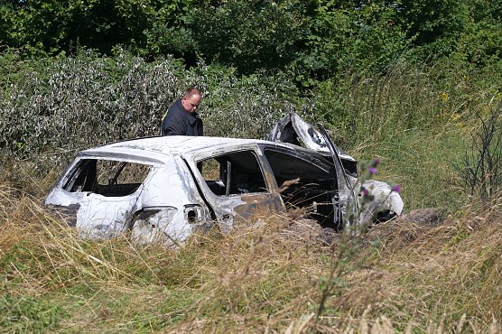 Polizisten untersuchen das ausgebrannte Wrack eines Dacias an der Ungl&uuml;cksstelle (Foto: S.Dietzel)
