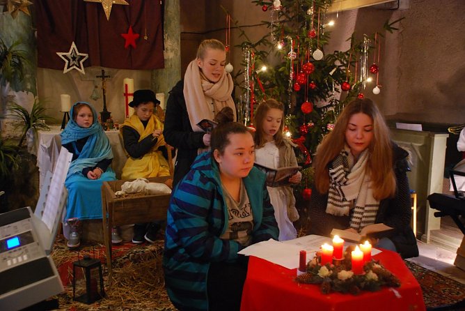 In dieser Szene sehen wir hinten Maria und Josef (Lotta und Leonhard) vor der Krippe sitzen, Letizia und Talia beim Singen des Liedes "Stille Nacht, heilige Nacht" und im Vordergrund Laura und Anna, welche die Rahmenhandlung spielen (Laura muss einen Aufsatz &uuml;ber Weihnachten schreiben, Anna erz&auml;hlt ihr die Weihnachtsgeschichte). (Foto: Jochen Miche)