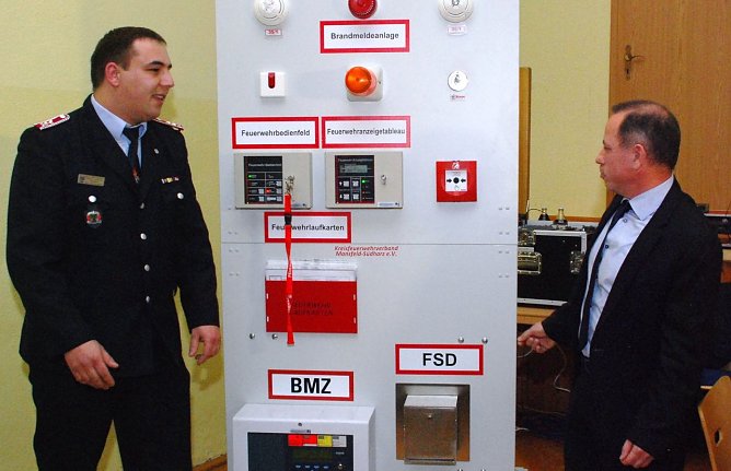 Offizielle Inbetriebnahme eines &uuml;beraus wertvollen Geschenks: Der Chef des Kreisfeuerwehrverbands, Roy Rockmann (links), nimmt von J&ouml;rg Fischer, Servicemanager der Wichmann Systemhausgruppe, die neue &Uuml;bungsbrandmeldeanlage entgegen. (Foto: Jochen Miche)