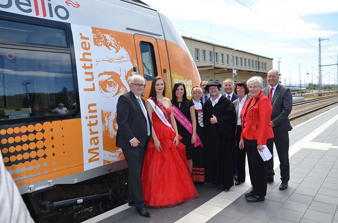 Im Bild vor dem "T&auml;ufling": Sangerhausens Oberb&uuml;rgermeister Ralf Poschmann, Rosenk&ouml;nigin Sophia, Bl&uuml;tenk&ouml;nigin Kristin, Katharina von Bora und Martin Luther, mittig dahinter: Peter Panitz, Chefplaner Nahverkehrsservice Sachsen-Anhalt GmbH (NASA), Mark Lange, Gesch&auml;ftsf&uuml;hrer der Standortmarketing Mansfeld-S&uuml;dharz GmbH, Landr&auml;tin Dr. Angelika Klein,  Eislebens Oberb&uuml;rgermeisterin Jutta Fischer. (Foto: Abellio Rail Mitteldeutschland)